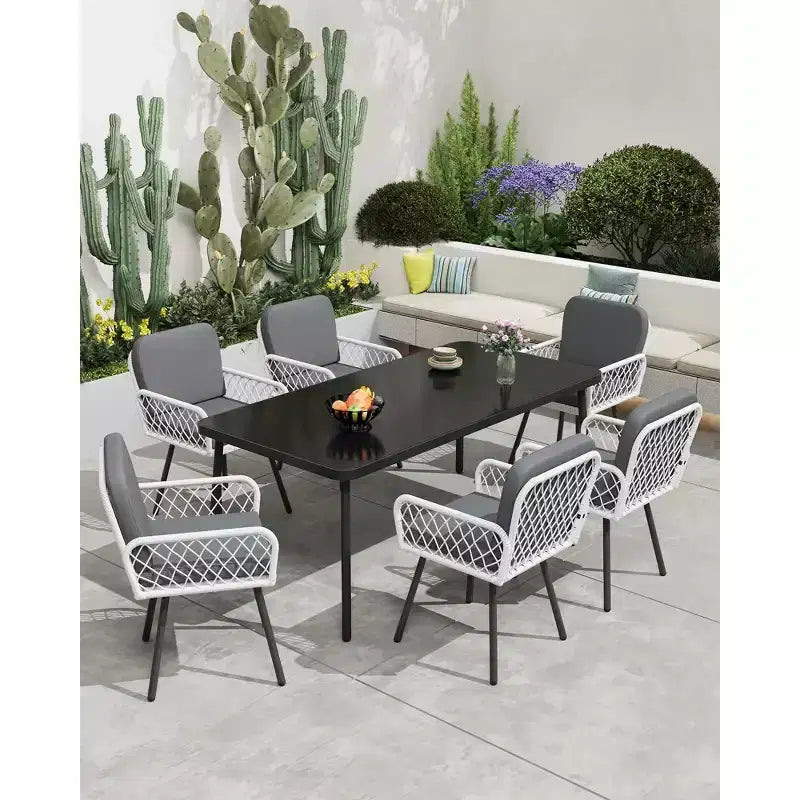 Set da pranzo da esterni 7 pezzi, tavolo con struttura in ferro 59x35 con piano in vetro temperato nero, 6 sedie in vimini PE resistenti alle intemperie con cuscini grigi